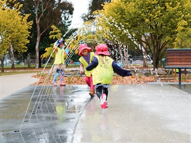 Children running in the new Ballam Park play space water play fountains