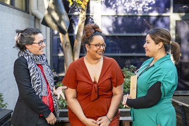 Three women standing and conversing with each other before the meeting begins