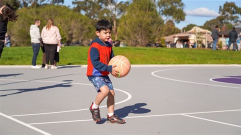 A child playing basketball on a multi-use court.