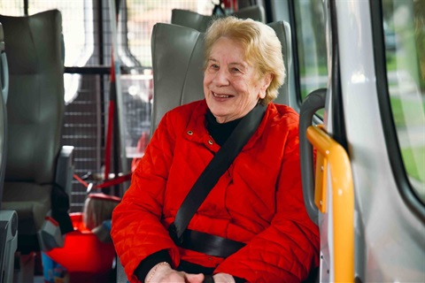 Elderly woman sitting on a bus smiling